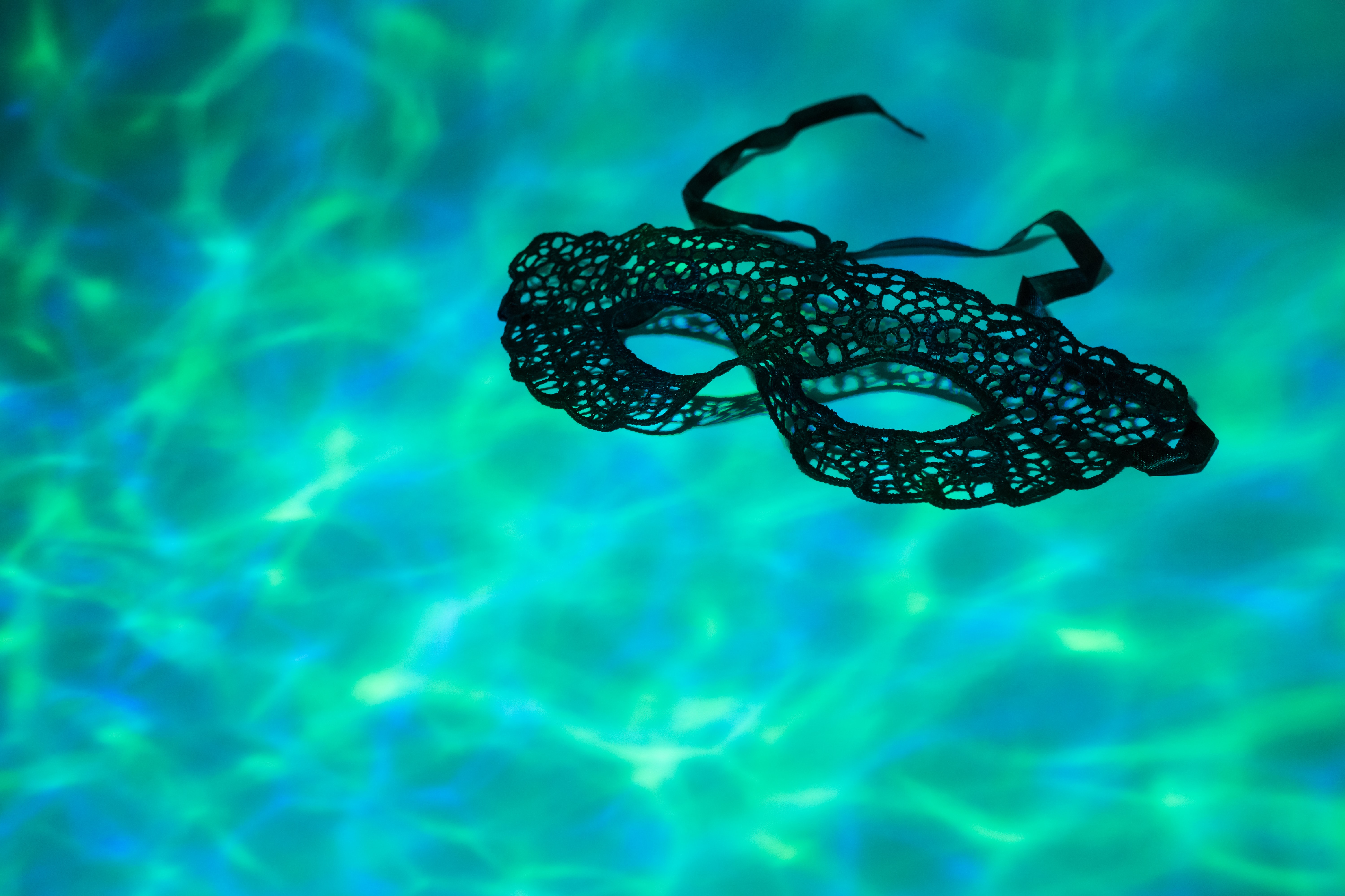 Schwarze Spitzenmaske schwimmt im Pool